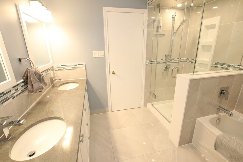 Modern bathroom renovation featuring dual sinks, sleek gray countertops, glass shower enclosure, and elegant tile design, showcasing Superior Bath's craftsmanship.