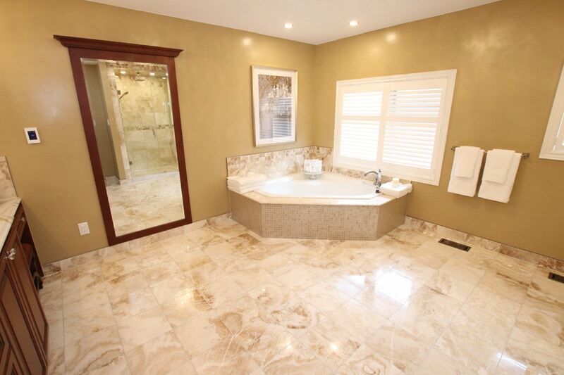 Luxurious bathroom renovation featuring a corner jetted tub, elegant marble flooring, modern fixtures, and natural light from large windows, showcasing Superior Bath's design expertise.