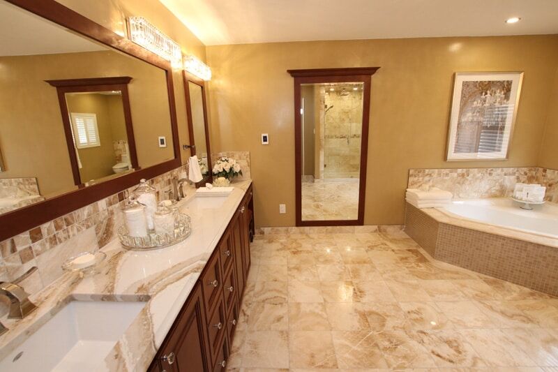 Luxurious bathroom with double vanity, marble countertops, elegant lighting, and spacious shower area, showcasing Superior Bath's custom renovation work.