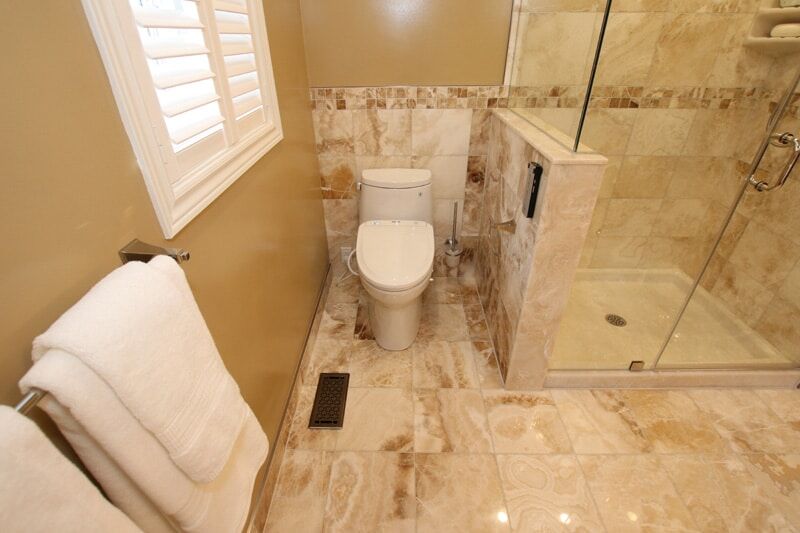 Modern bathroom featuring a glass shower, elegant marble flooring, and a white toilet, showcasing Superior Bath's custom renovation craftsmanship.