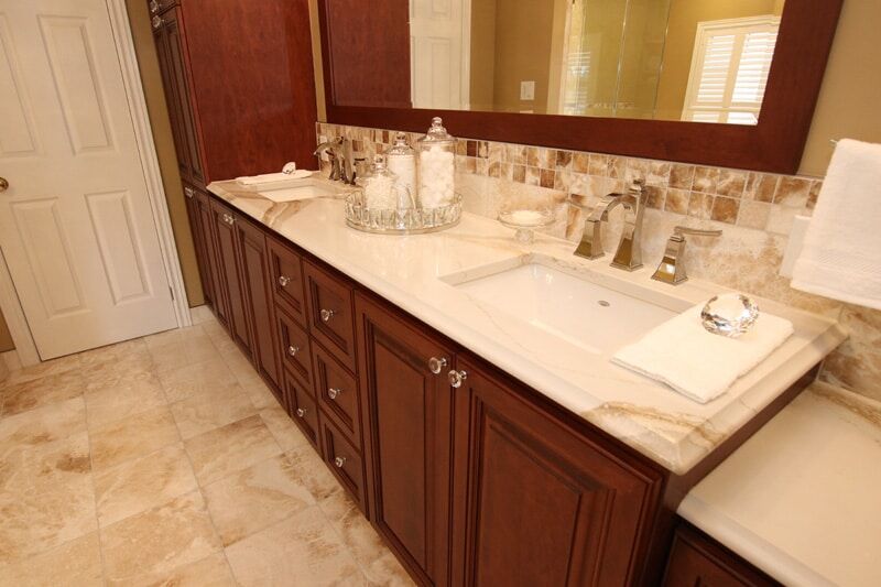 Modern bathroom vanity with dark wood cabinetry, marble countertop, contemporary faucet, and decorative accessories, showcasing Superior Bath's custom renovation work.