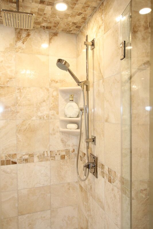 Modern shower with rainfall showerhead, sleek chrome fixtures, and beige marble tiles, showcasing a luxurious bathroom renovation by Superior Bath.