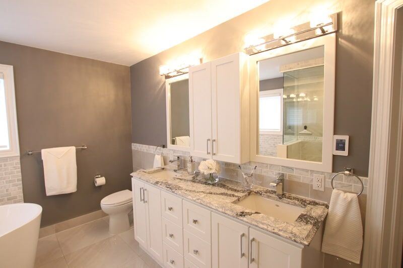 Modern bathroom renovation featuring a double vanity with granite countertop, stylish mirrors, and contemporary lighting, showcasing Superior Bath's craftsmanship and design expertise.