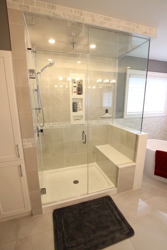 Modern glass shower enclosure with built-in shelving, tiled walls, and a sleek bench, showcasing a custom bathroom renovation by Superior Bath.