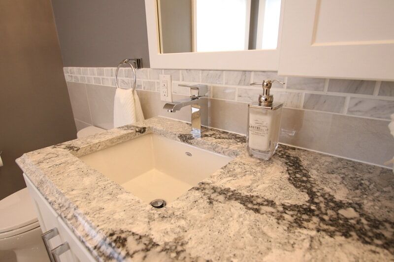 Modern bathroom sink with a granite countertop, stylish faucet, and decorative soap dispenser, showcasing Superior Bath's custom renovation work.