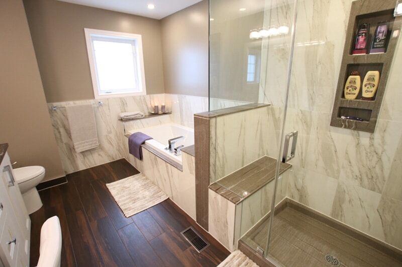 Modern bathroom renovation featuring a glass shower, freestanding tub, marble tiles, and stylish wooden flooring, showcasing Superior Bath's craftsmanship and design.