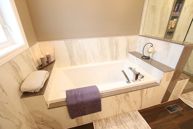 Modern bathroom with a freestanding tub, marble walls, soft towels, and candles, showcasing Superior Bath's custom renovation style.