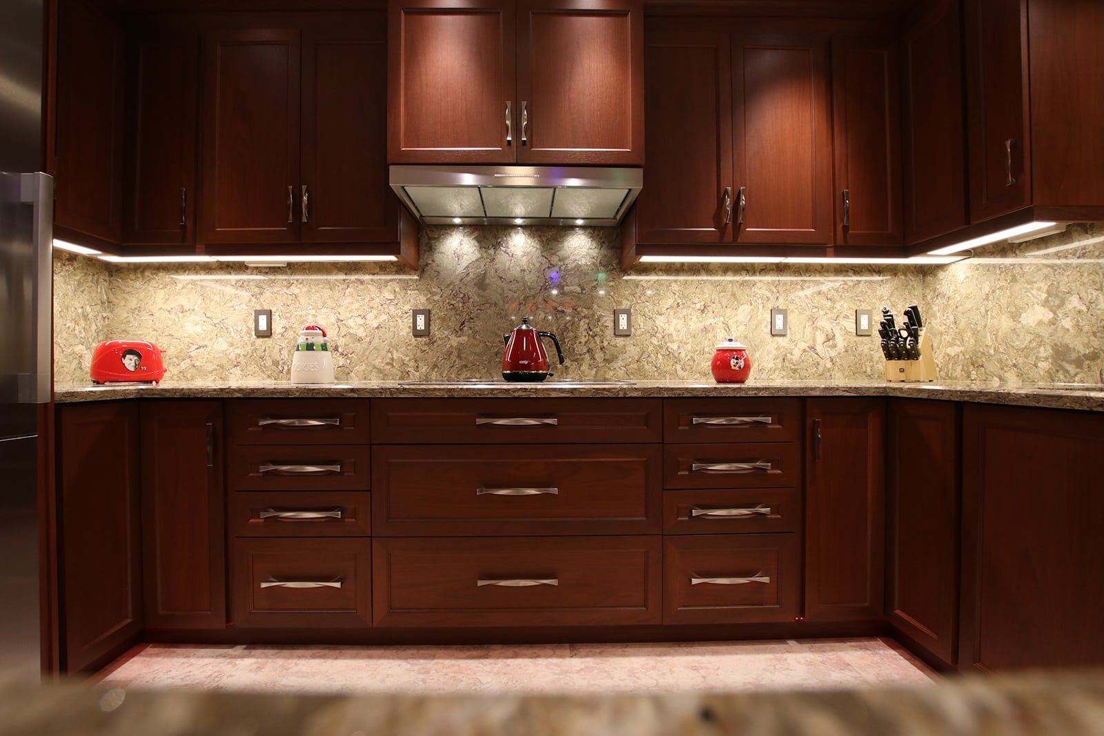 Modern kitchen with dark wood cabinetry, granite countertops, red kettle, and decorative accessories, showcasing Superior Bath's kitchen renovation expertise.