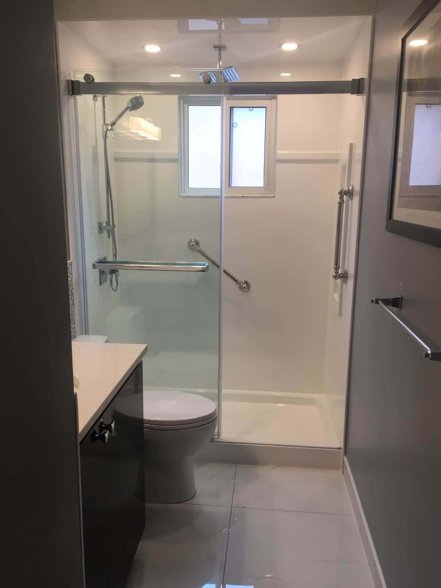 Modern bathroom with glass shower enclosure, chrome fixtures, white tiles, and a toilet, showcasing Superior Bath's custom renovation work.