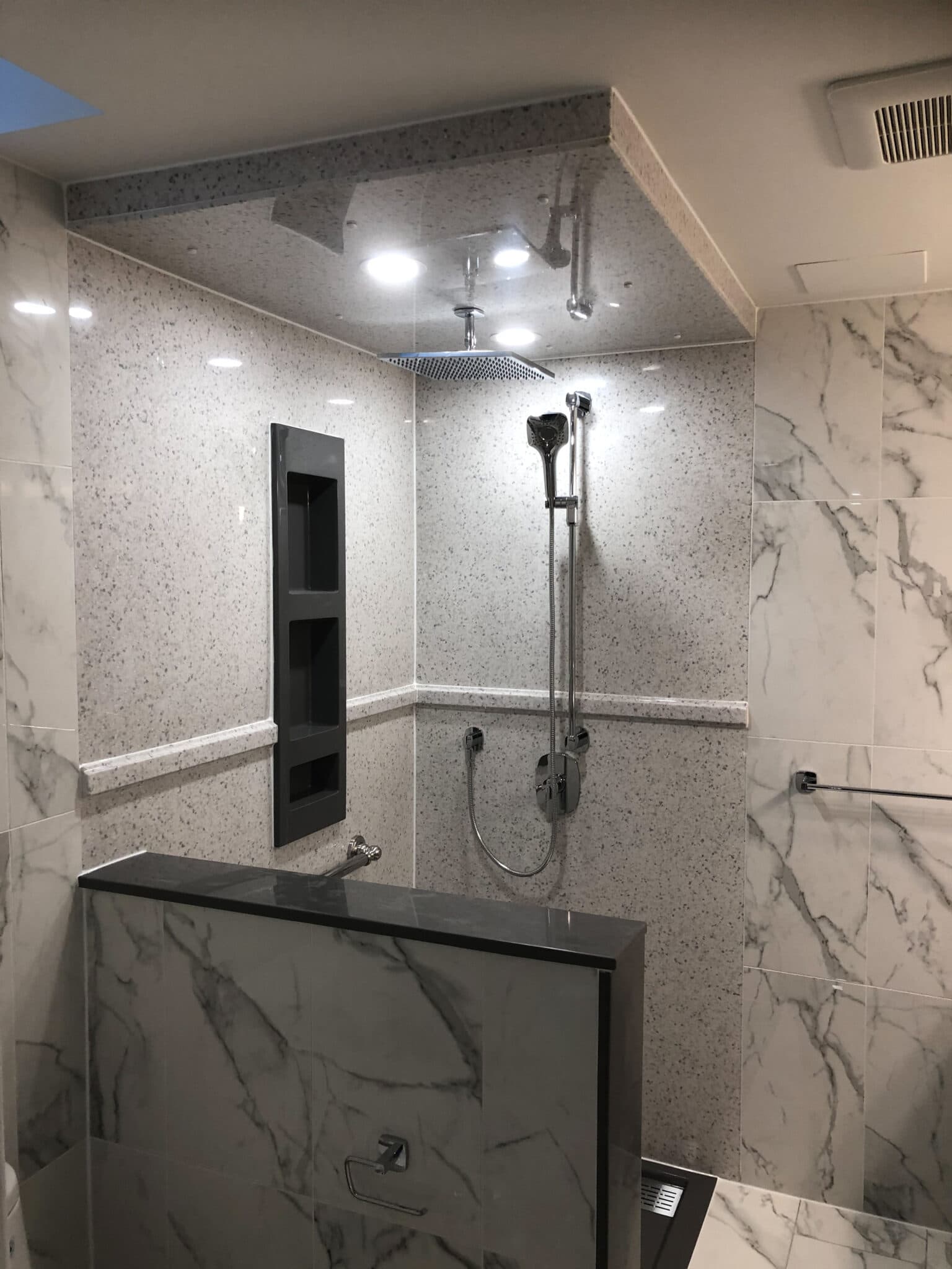 Modern bathroom design featuring a sleek shower area with marble walls, recessed lighting, and a minimalist shower fixture, showcasing Superior Bath's custom renovation capabilities.