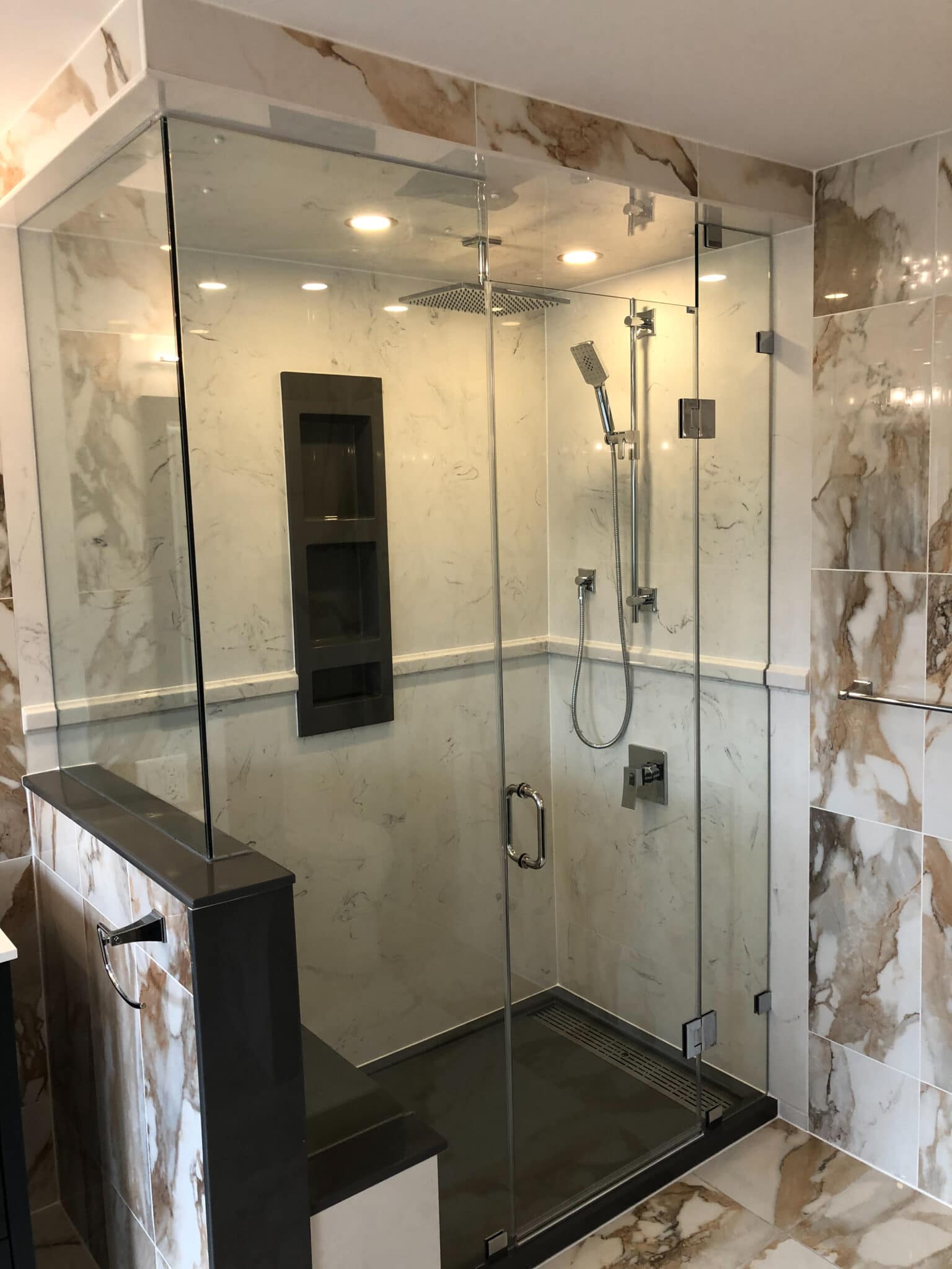 Custom glass shower enclosure with modern fixtures and marble tile accents in a renovated bathroom by Superior Bath.