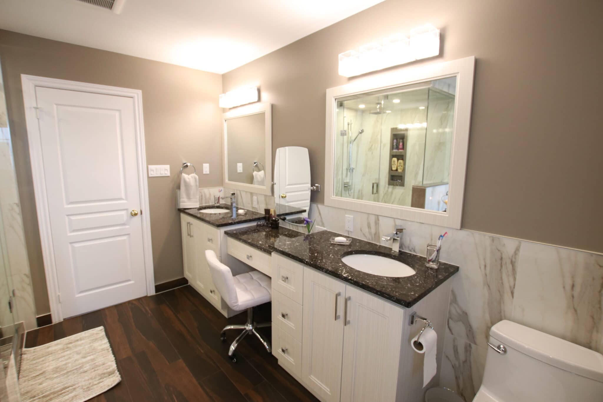 Modern bathroom design featuring dual vanities with dark granite countertops, stylish mirrors, a walk-in shower, and elegant fixtures, showcasing Superior Bath's custom renovation work.