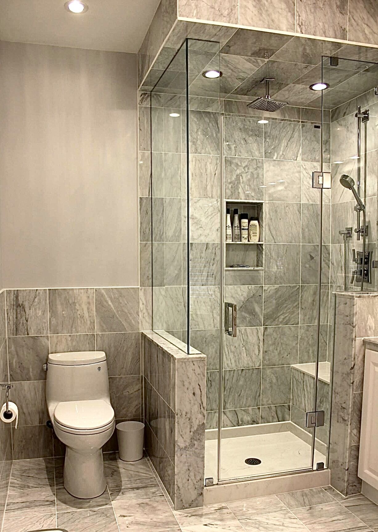 Modern bathroom renovation featuring a glass shower enclosure, marble tile walls, and a contemporary toilet, showcasing Superior Bath's craftsmanship.