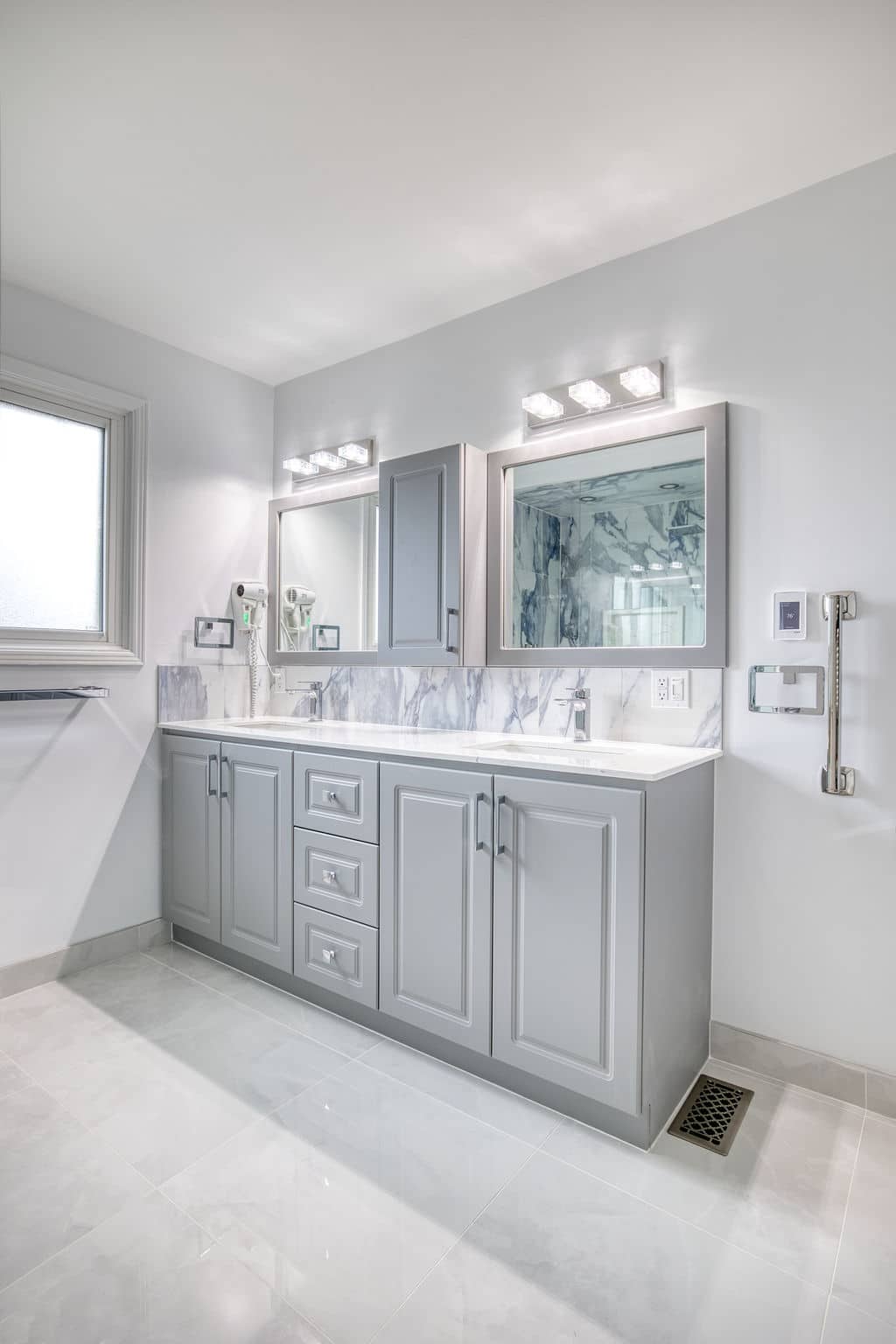 Modern bathroom with gray cabinetry, marble countertop, dual mirrors, and contemporary lighting, showcasing Superior Bath's custom renovation style.