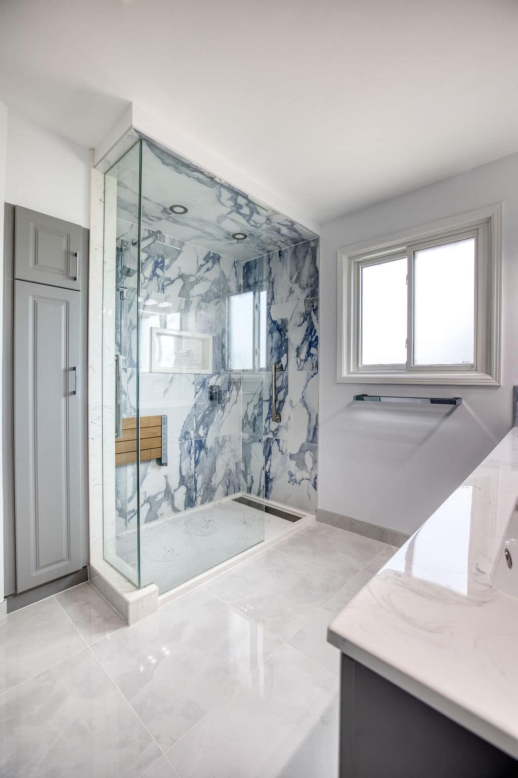 Modern bathroom featuring a glass shower with blue and white marble walls, sleek fixtures, and a bright, airy atmosphere, showcasing Superior Bath's custom renovation work.