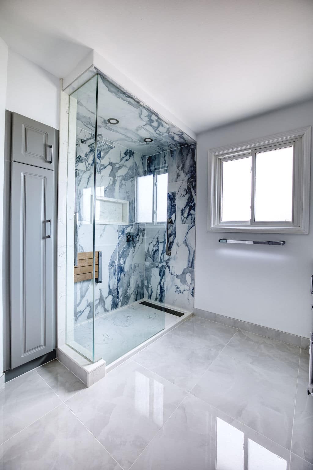 Custom bathroom renovation featuring a modern glass shower with marble walls, sleek tile flooring, and natural light from a window, showcasing Superior Bath's craftsmanship and design capabilities.