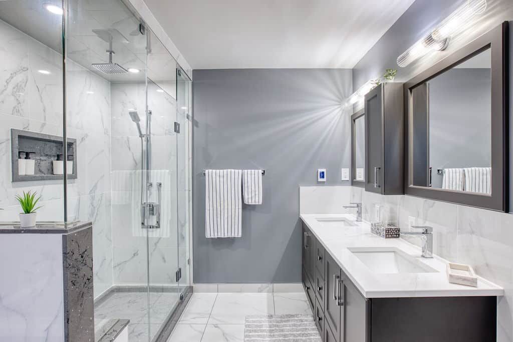 Modern bathroom renovation featuring a glass shower, dual sinks, marble accents, and stylish cabinetry by Superior Bath.