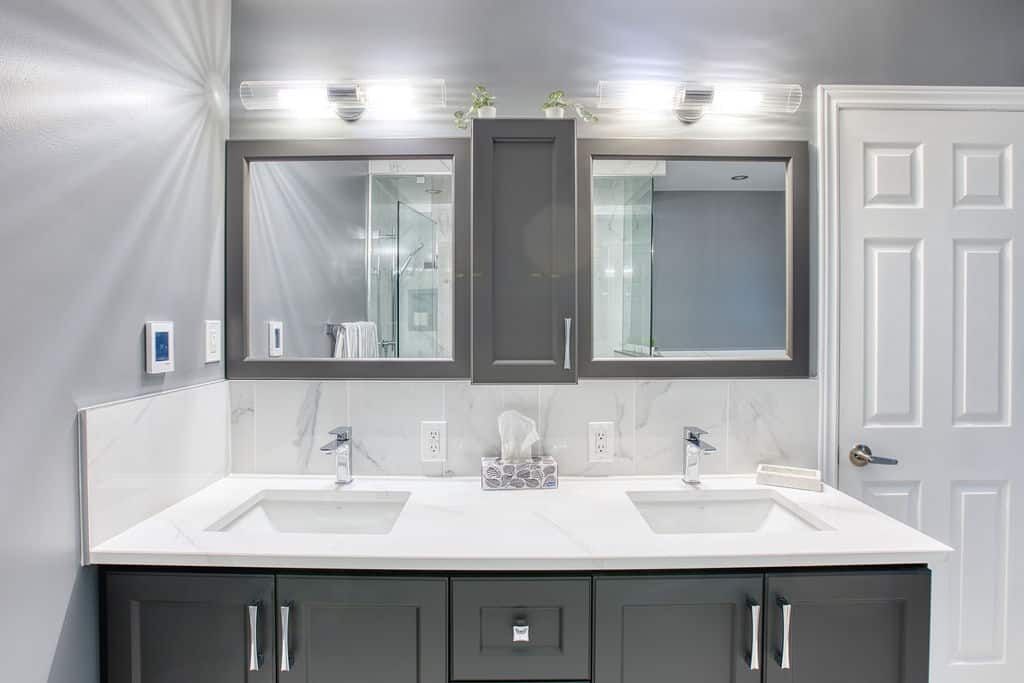Modern bathroom vanity with dual sinks, gray cabinetry, and stylish mirrors, showcasing Superior Bath's custom renovation work.