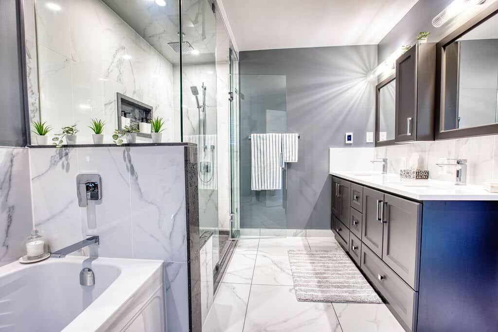 Modern bathroom renovation featuring a freestanding tub, glass shower enclosure, dual vanities with dark cabinetry, and elegant marble accents, showcasing Superior Bath's craftsmanship.