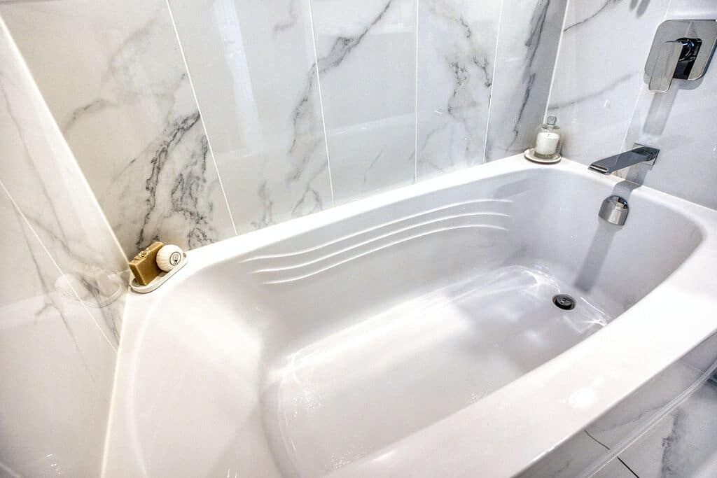 Custom bathroom with a modern freestanding tub, marble wall tiles, and sleek faucet, showcasing Superior Bath's renovation craftsmanship.