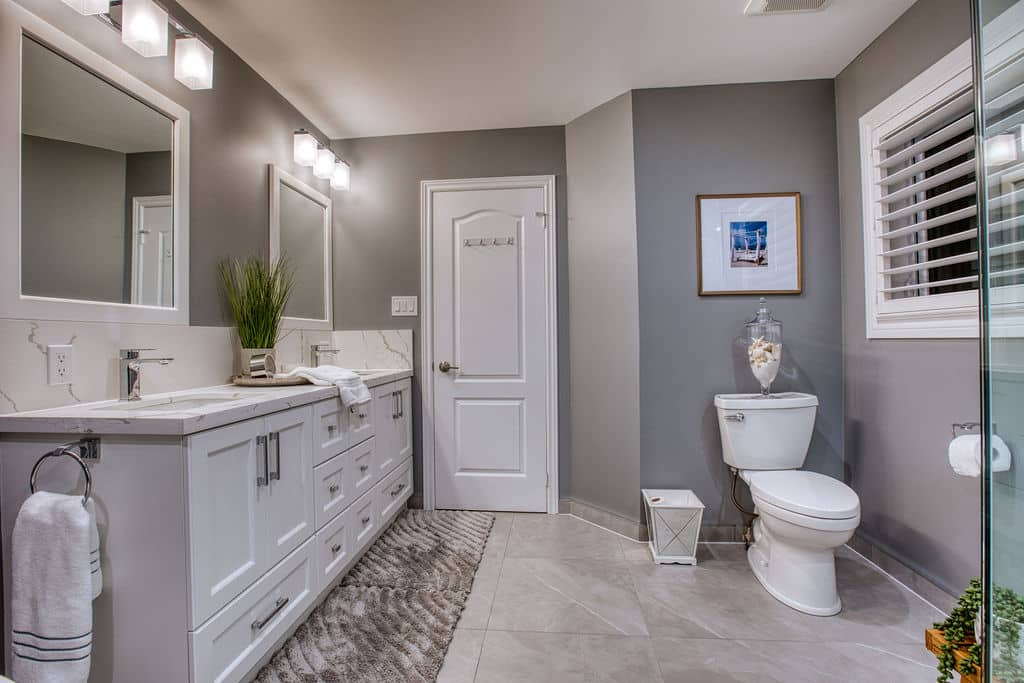 Modern custom bathroom with white cabinetry, dual mirrors, decorative plants, and a stylish shower area, showcasing Superior Bath's renovation expertise.