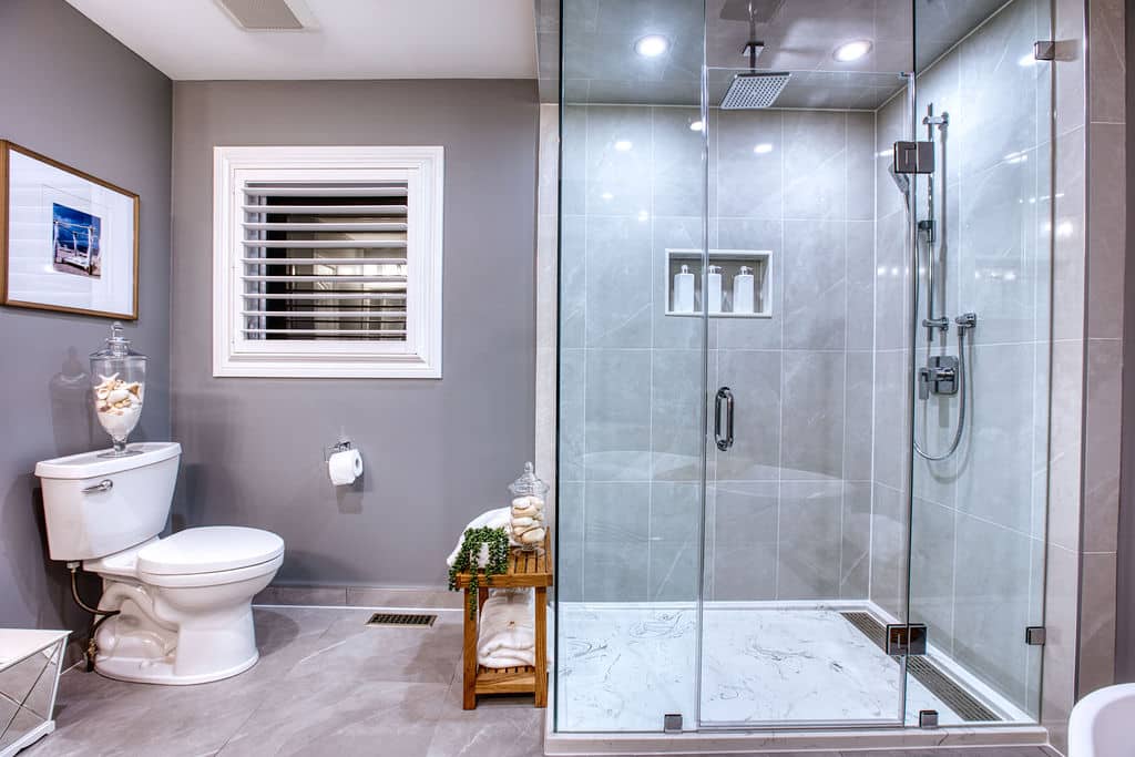 Modern bathroom design featuring a glass shower enclosure, white toilet, and decorative elements like a framed picture and towel display, showcasing Superior Bath's custom renovation work.