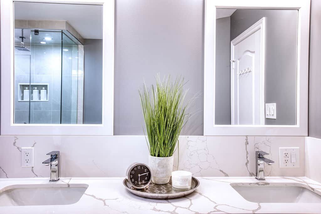 Custom bathroom vanity with dual mirrors, modern faucets, decorative plant, and stylish accessories, showcasing Superior Bath's renovation craftsmanship.