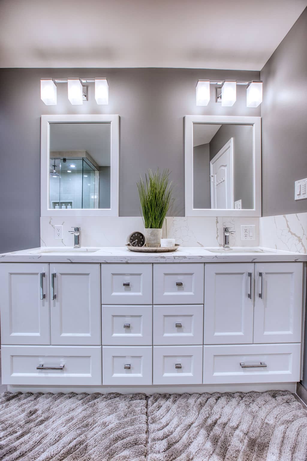 Modern bathroom vanity with white cabinetry, double mirrors, sleek sink, decorative plant, and stylish lighting, showcasing Superior Bath's custom renovation design.