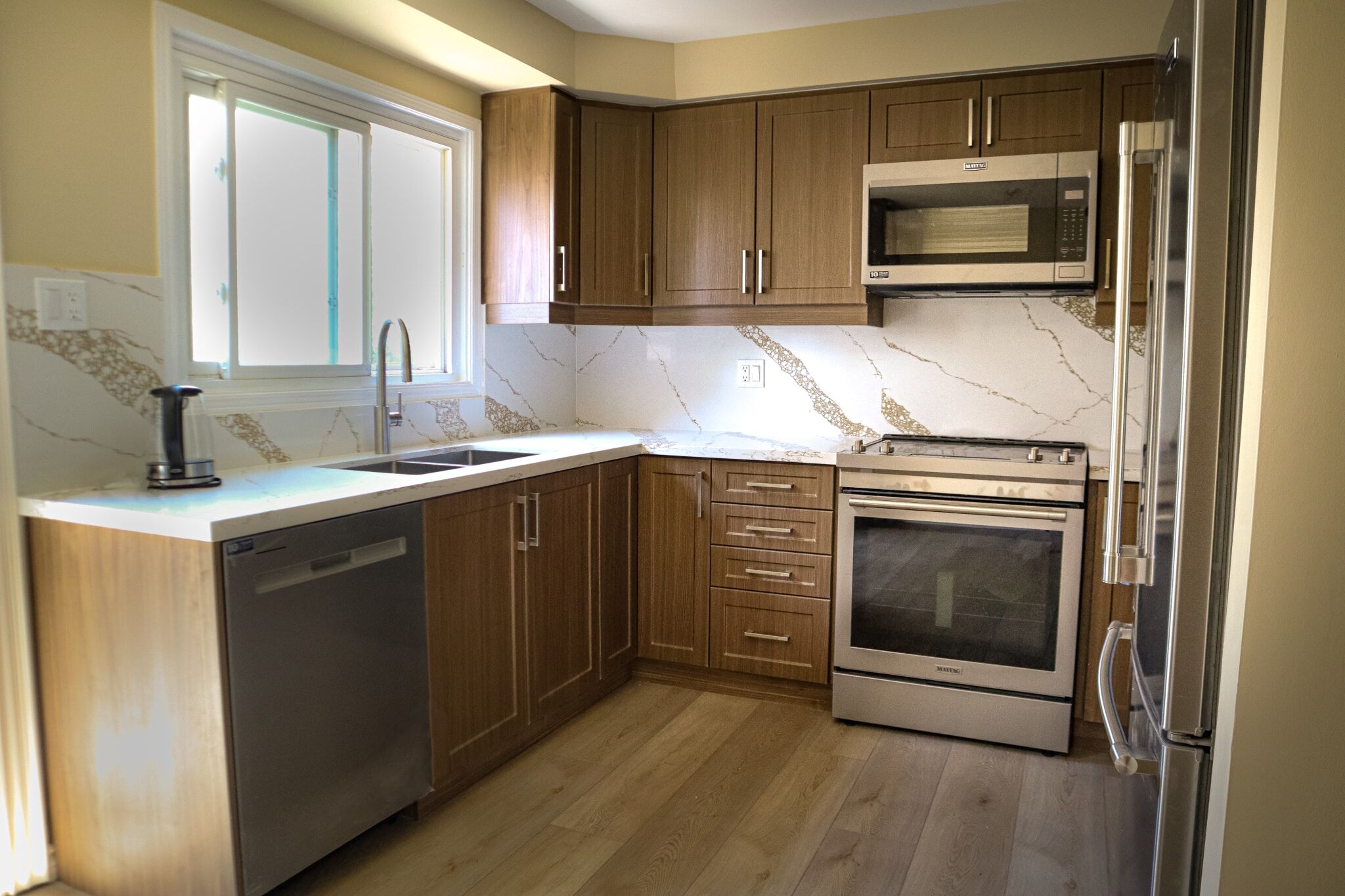 Modern kitchen renovation featuring wooden cabinetry, stainless steel appliances, and a marble backsplash, showcasing Superior Bath's design expertise.