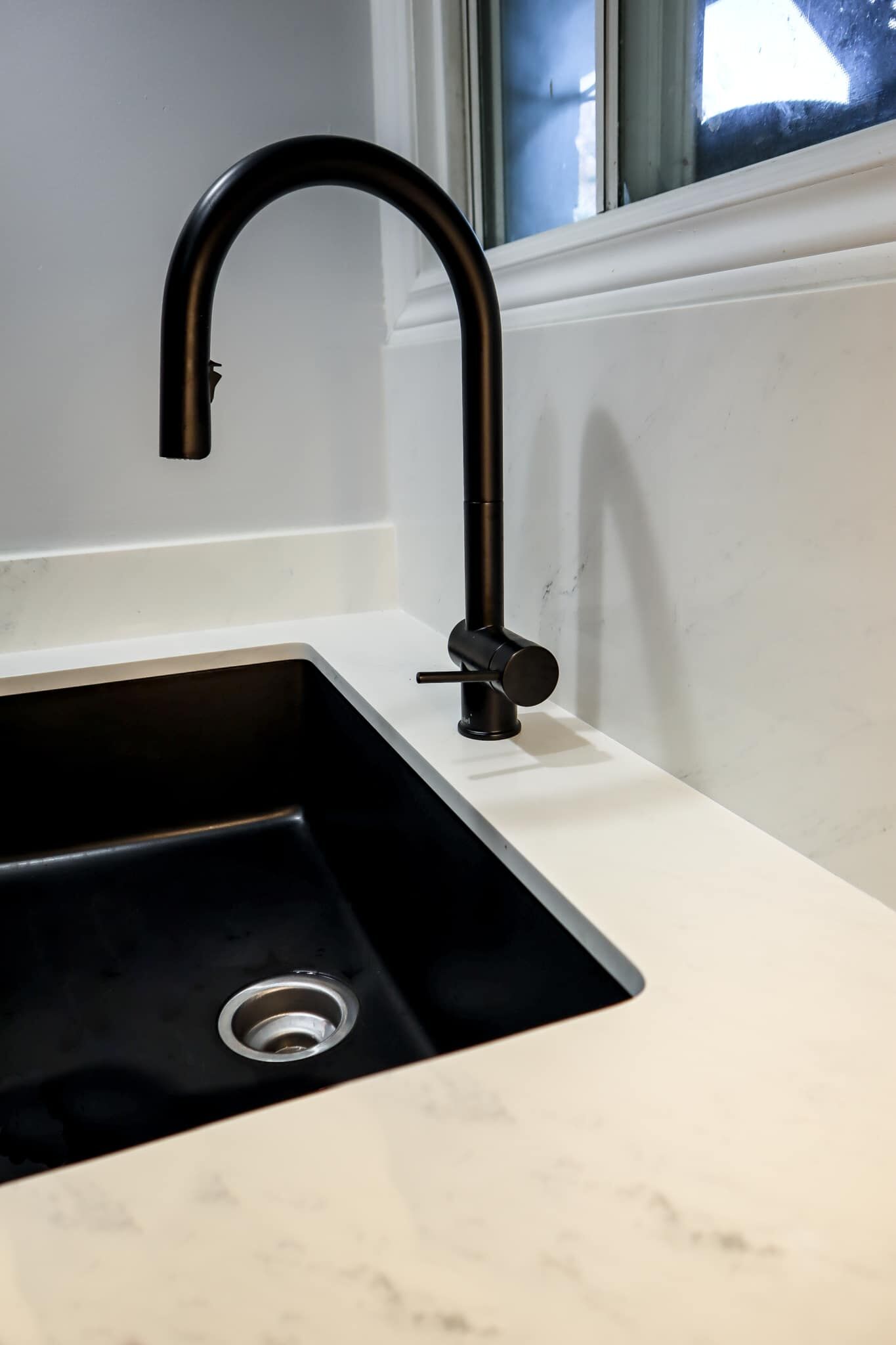 Black kitchen sink with modern faucet and white countertop, showcasing Superior Bath's renovation style.