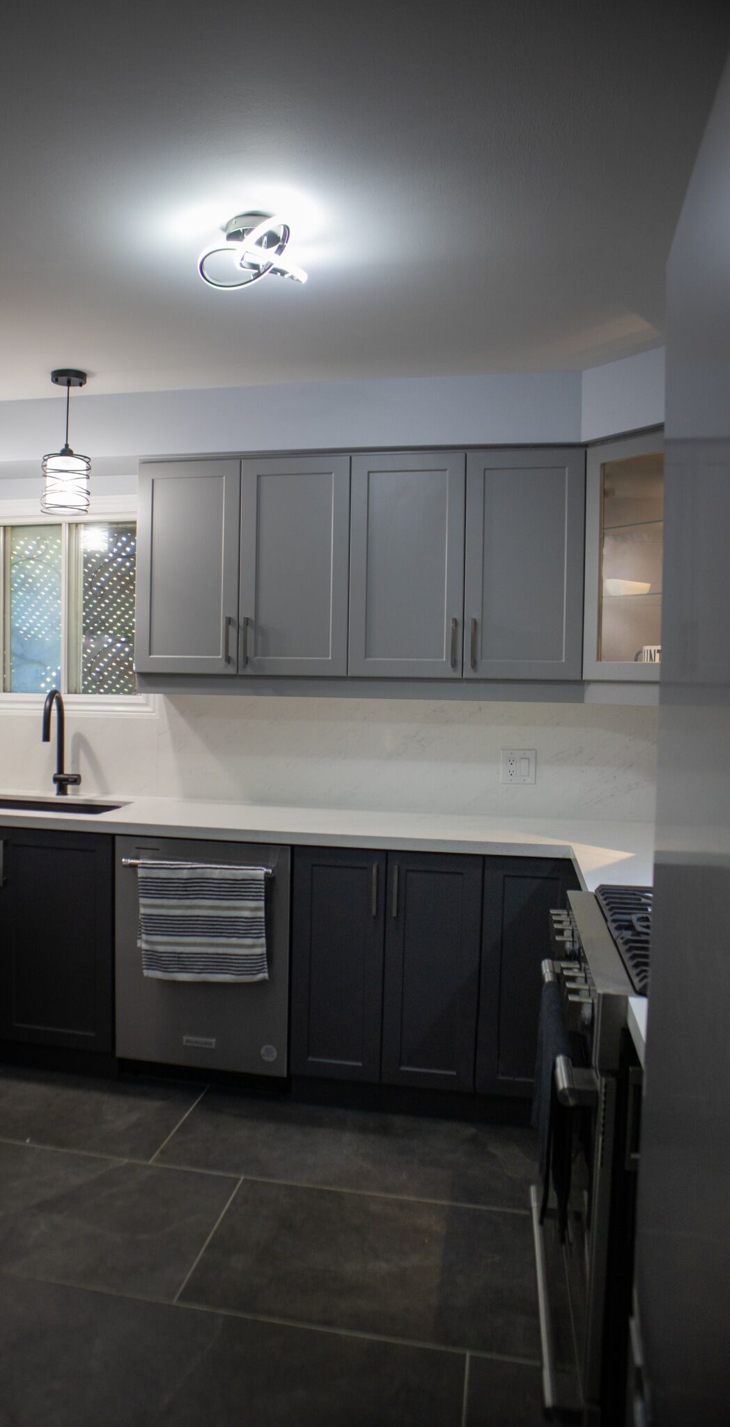 Modern kitchen design featuring gray cabinetry, stainless steel appliances, and contemporary lighting fixtures, showcasing Superior Bath's kitchen renovation expertise.