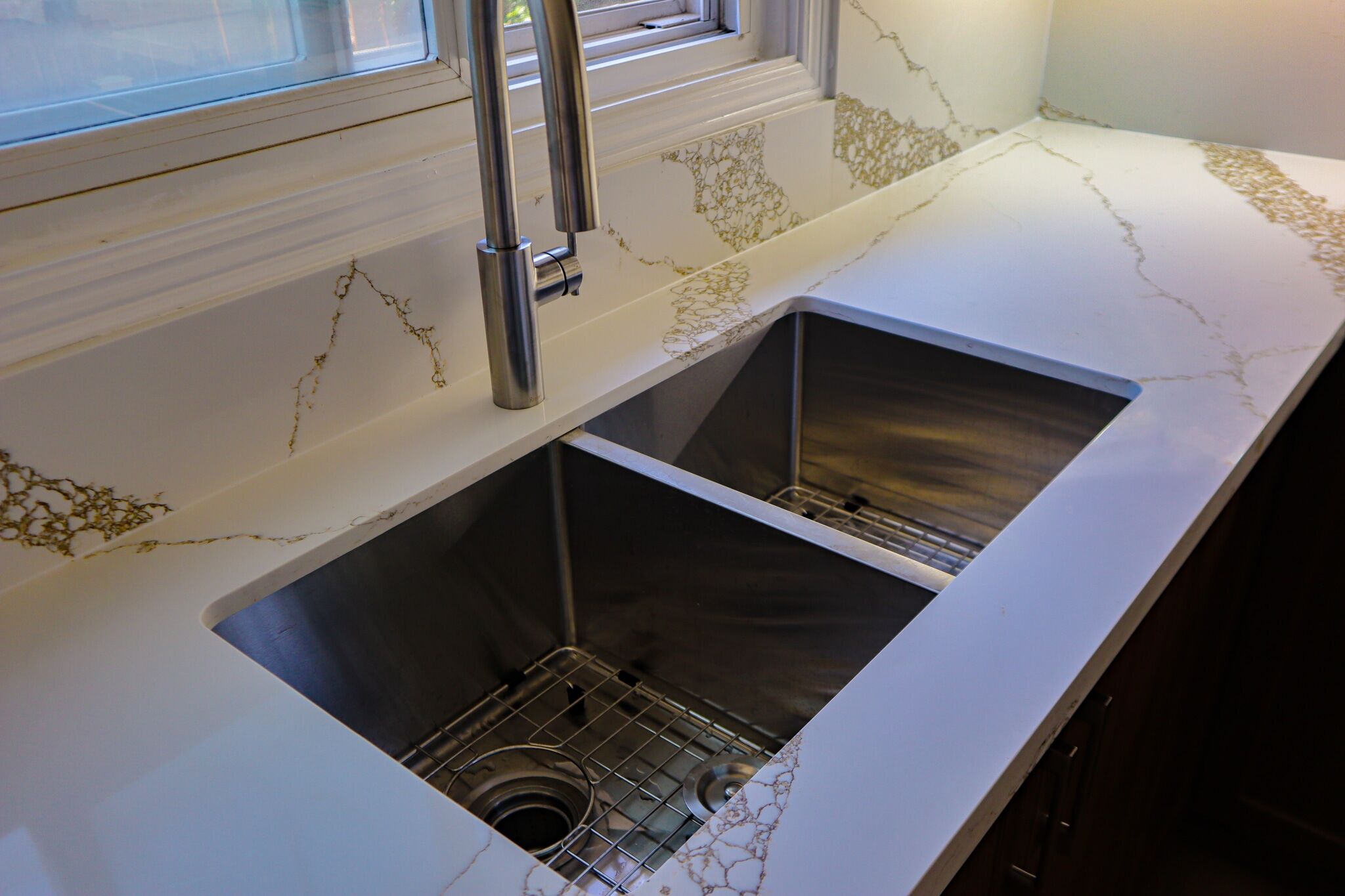 Modern kitchen sink with dual stainless steel basins, sleek marble countertop featuring gold veining, and contemporary faucet design, showcasing Superior Bath's kitchen renovation expertise.