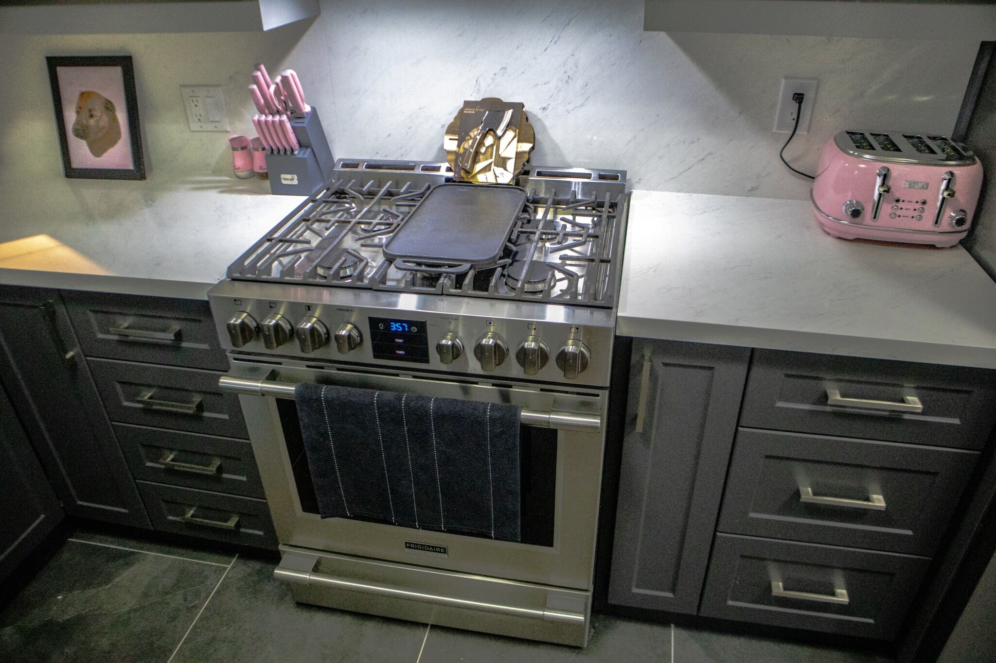Modern kitchen featuring a stainless steel gas range, black cooking griddle, pink toaster, and pink kitchen utensils, showcasing Superior Bath's kitchen renovation design.