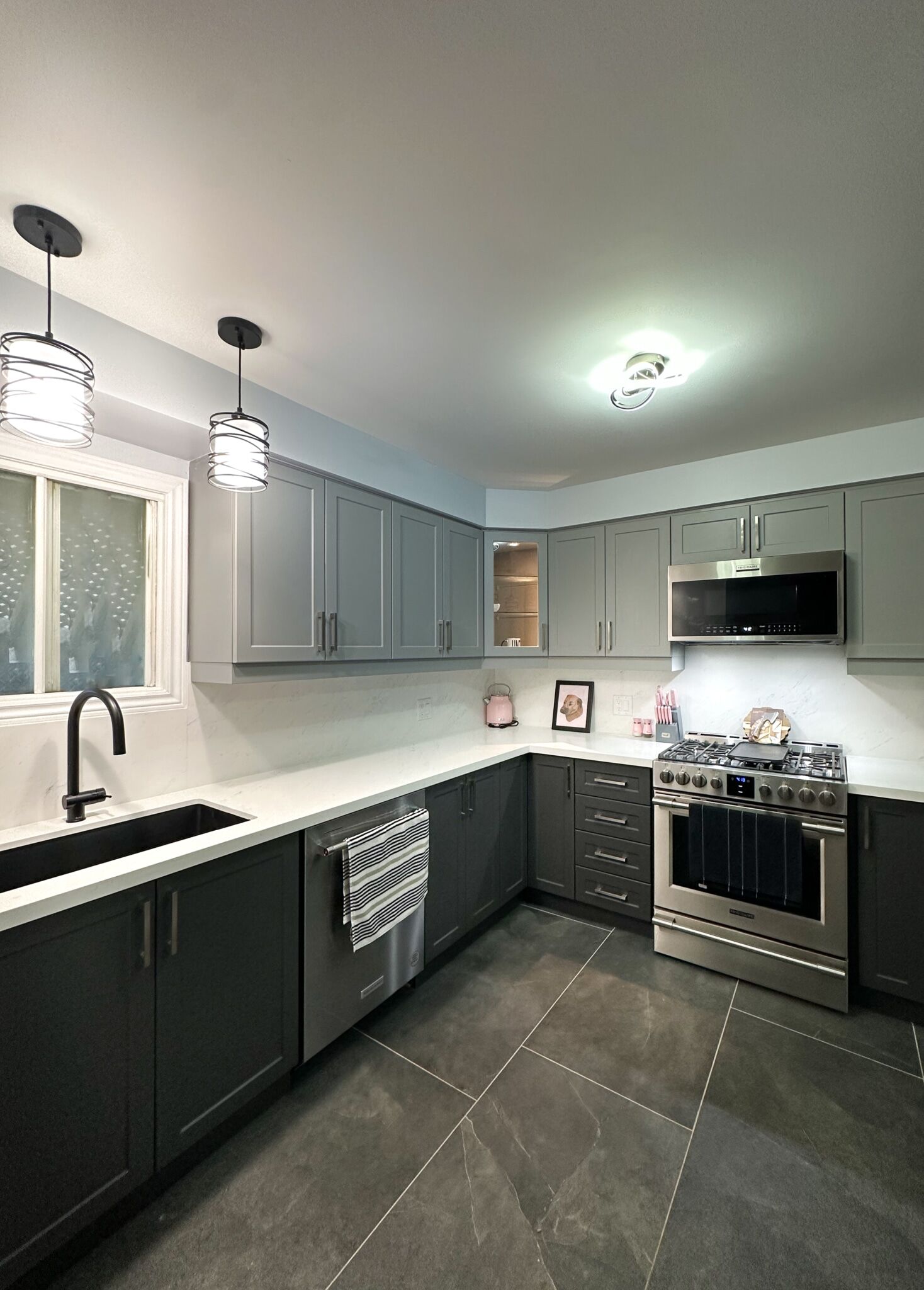Modern kitchen renovation featuring gray cabinetry, stainless steel appliances, black sink, and pendant lighting, showcasing Superior Bath's design expertise.
