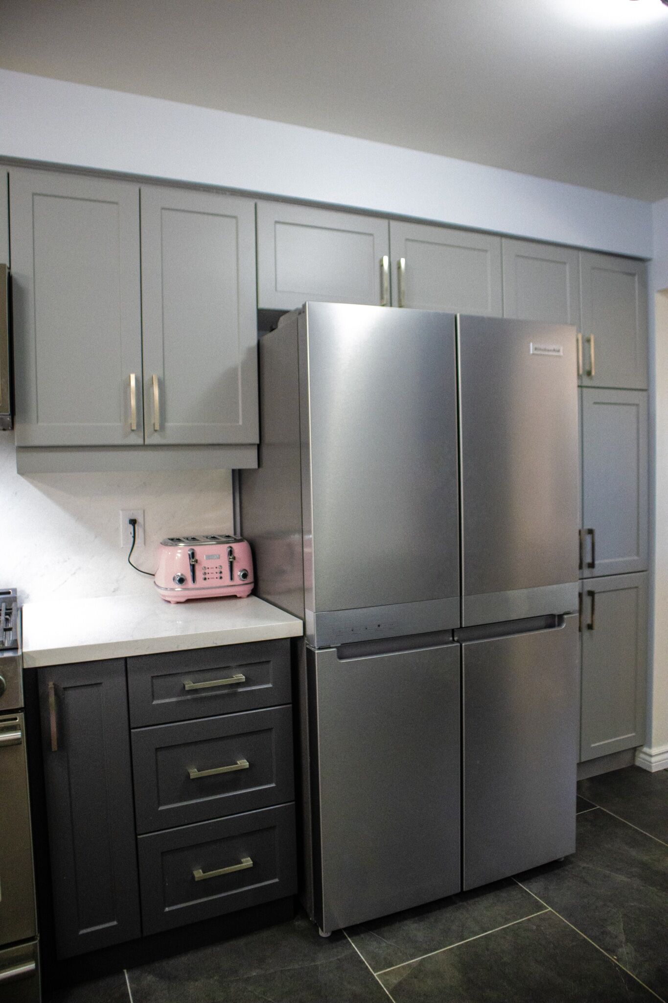 Modern kitchen featuring a stainless steel refrigerator, gray cabinetry, and a pink toaster on a white countertop, showcasing Superior Bath's kitchen renovation style.