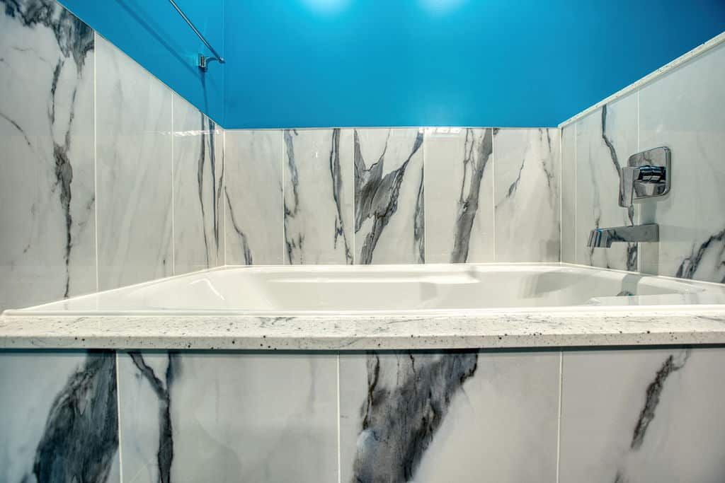 Custom bathroom with modern white tub, marble-patterned wall tiles, and vibrant blue accents, showcasing Superior Bath's renovation expertise.