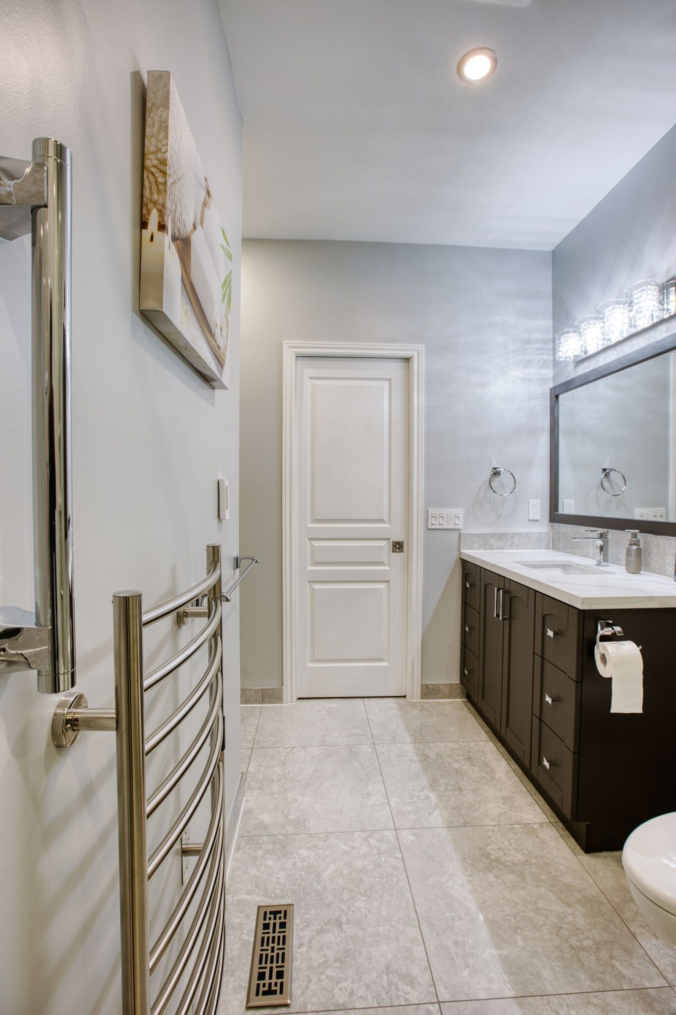 Modern bathroom interior featuring a sleek vanity with dark cabinetry, a large mirror, stylish lighting, and a towel warmer, showcasing Superior Bath's custom renovation work.