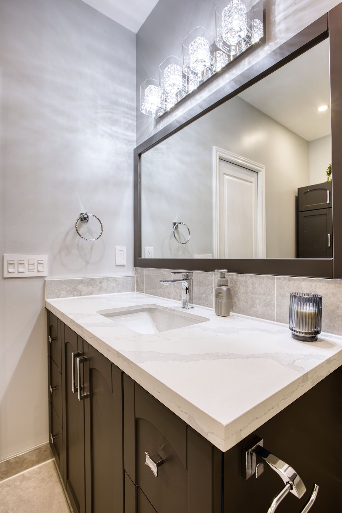 Modern bathroom vanity with a sleek white countertop, contemporary faucet, and elegant lighting fixtures above a large mirror, showcasing Superior Bath's custom renovation style.